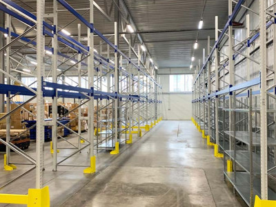 Professional image of a team installing modern warehouse shelving units. The shelves are being carefully positioned and secured, with all team members wearing protective gear and using specialized equipment to ensure precise installation.